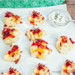 Loaded Cauliflower Bites on white plate with sour cream