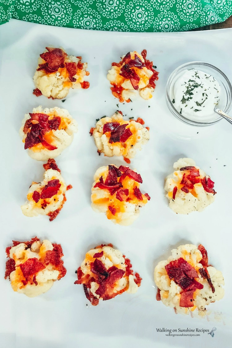Loaded Smashed Cauliflower Bites on white tray with sour cream and chives