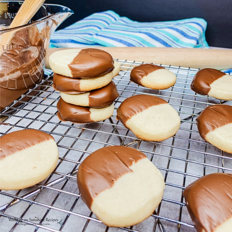 Slice and Bake Shortbread Cookies are a light, buttery cookie. Freezing tips included so you can prep ahead for all your cookie baking needs from Walking on Sunshine Recipes. Slice and Bake Shortbread Cookies dipped in melted chocolate stacked on wire baking rack.