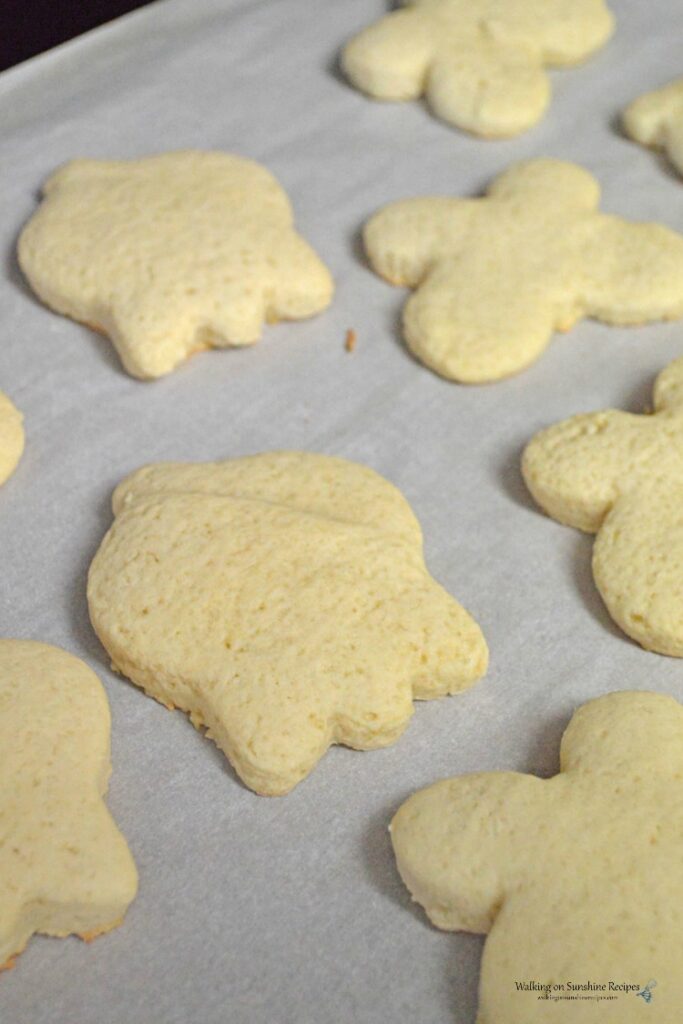 Baked sugar cookies on baking tray lined with parchment paper.