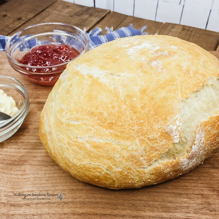 Loaf of Rustic Bread on Cutting Board with butter and jam. 