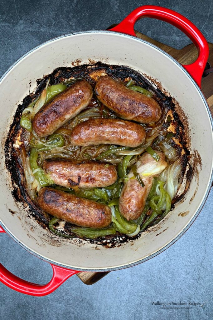 Sausage and Peppers in red casserole dish on cutting board from WOS