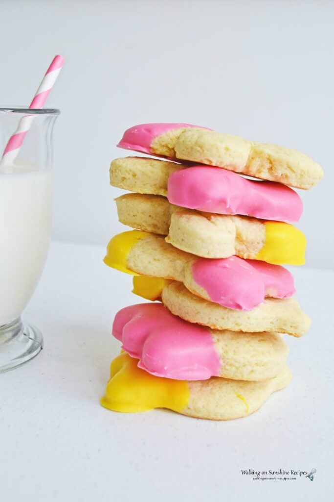 Spring Sugar cookies stacked with glass of milk.