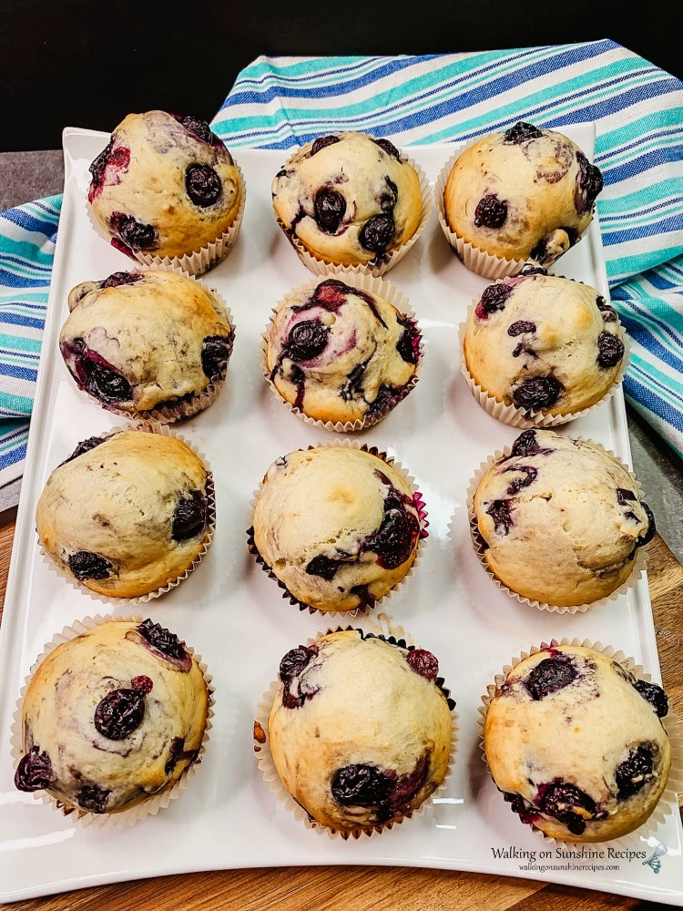 Blueberry Muffins on white tray with blue striped dish towel from Walking on Sunshine Recipes