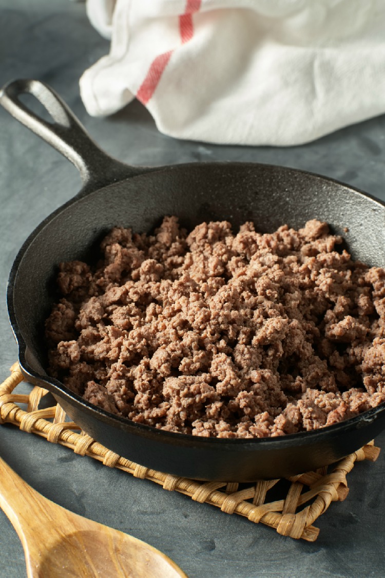 Browned Ground Beef in Cast Iron Skillet with wooden spoon