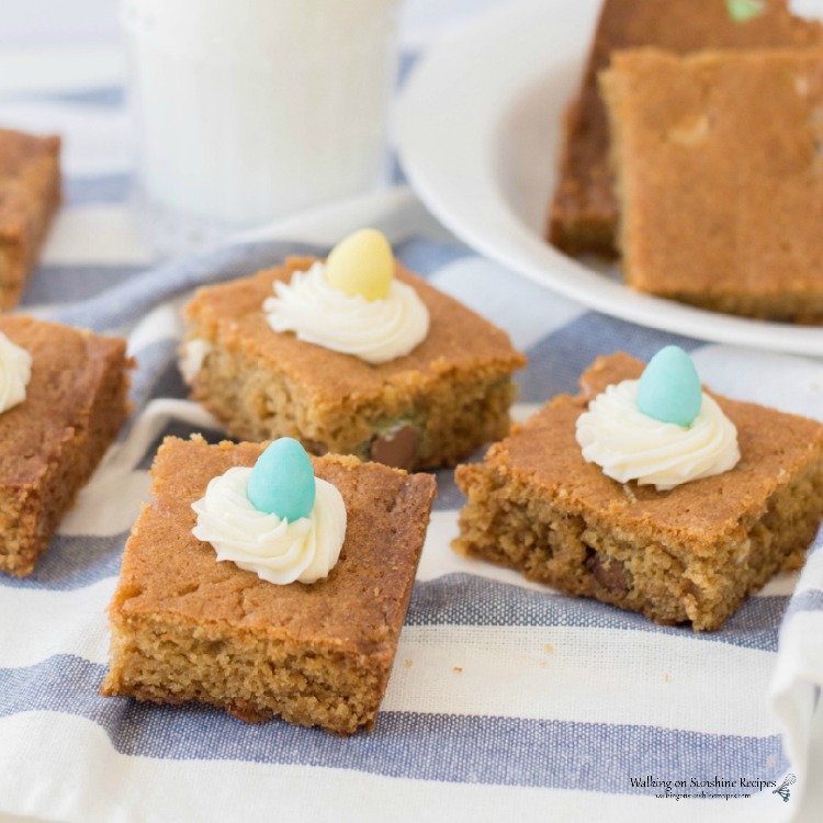 Candy Cookie Bars on plate with homemade cream cheese frosting swirls on top.
