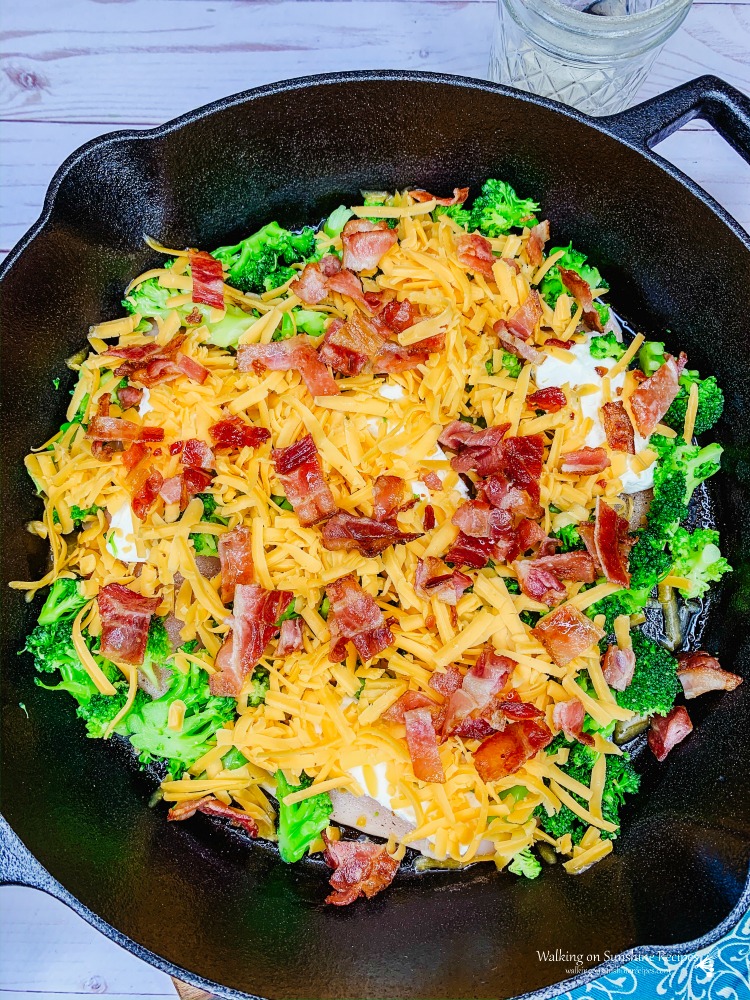 Chicken with broccoli, cheese and bacon in cast iron pan before baking. 