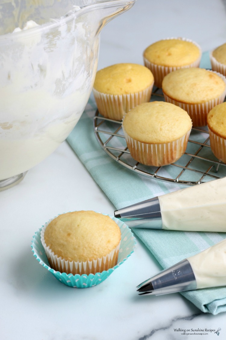 Homemade Cream Cheese Frosting in piping bags and cake mix vanilla cupcakes. 