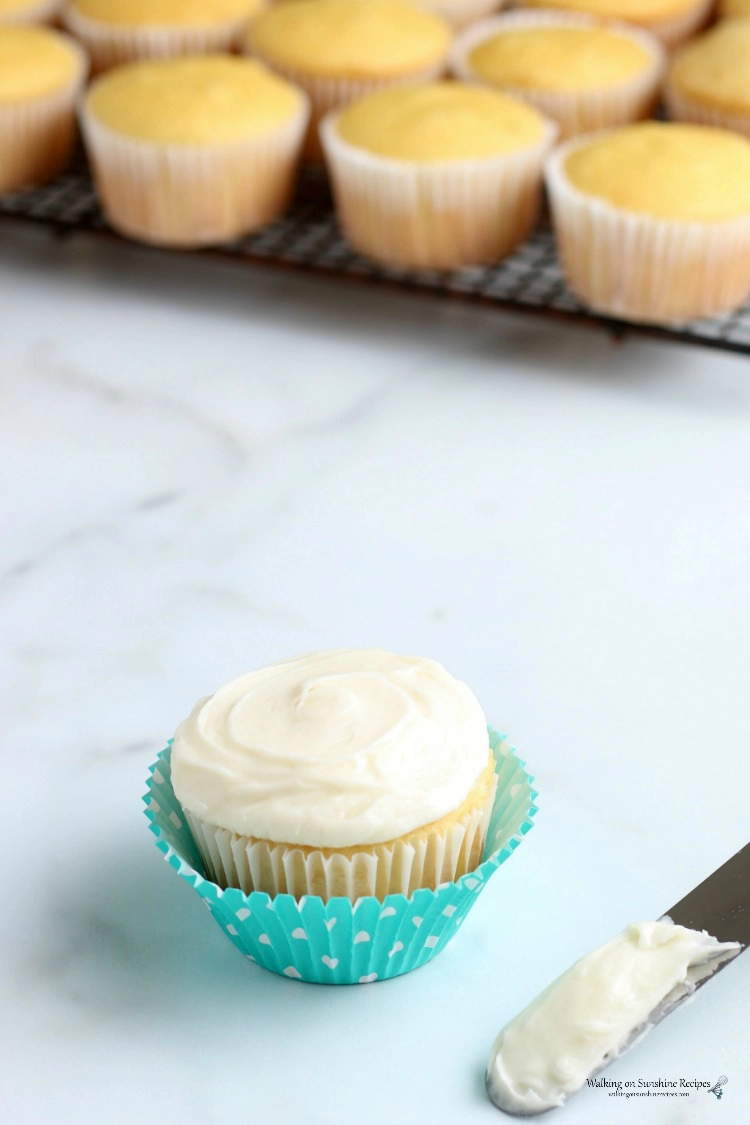 Vanilla cupcake with cream cheese frosting and off-set spatula. 
