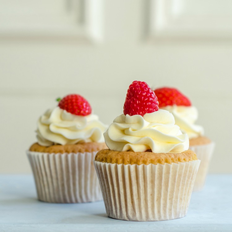 Vanilla Cupcakes with Homemade Cream Cheese Frosting and fresh raspberries on top.
