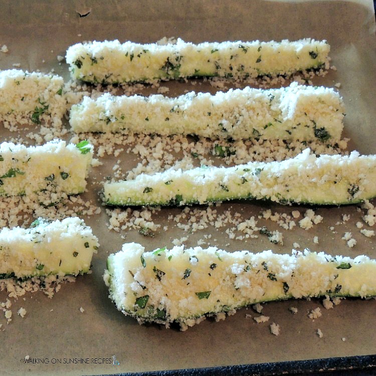 Zucchini sticks with panko breadcrumbs and Parmesan cheese on baking try ready for the oven.