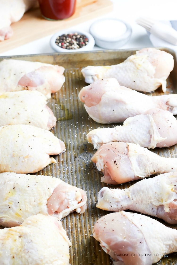 Raw chicken on baking tray sprinkled with salt and pepper ready for grill