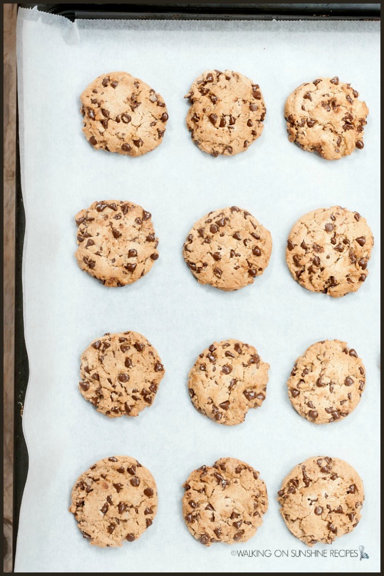 12 chocolate chip cookies baked on baking tray lined with parchment paper. 