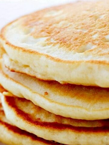 A close-up of a stack of fluffy pancakes with a golden crust.