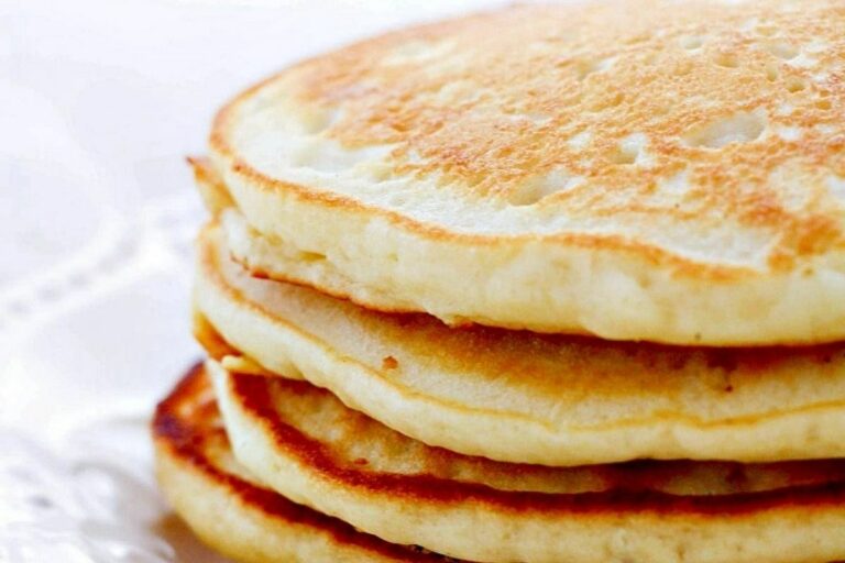 A close-up of a stack of fluffy pancakes with a golden crust.