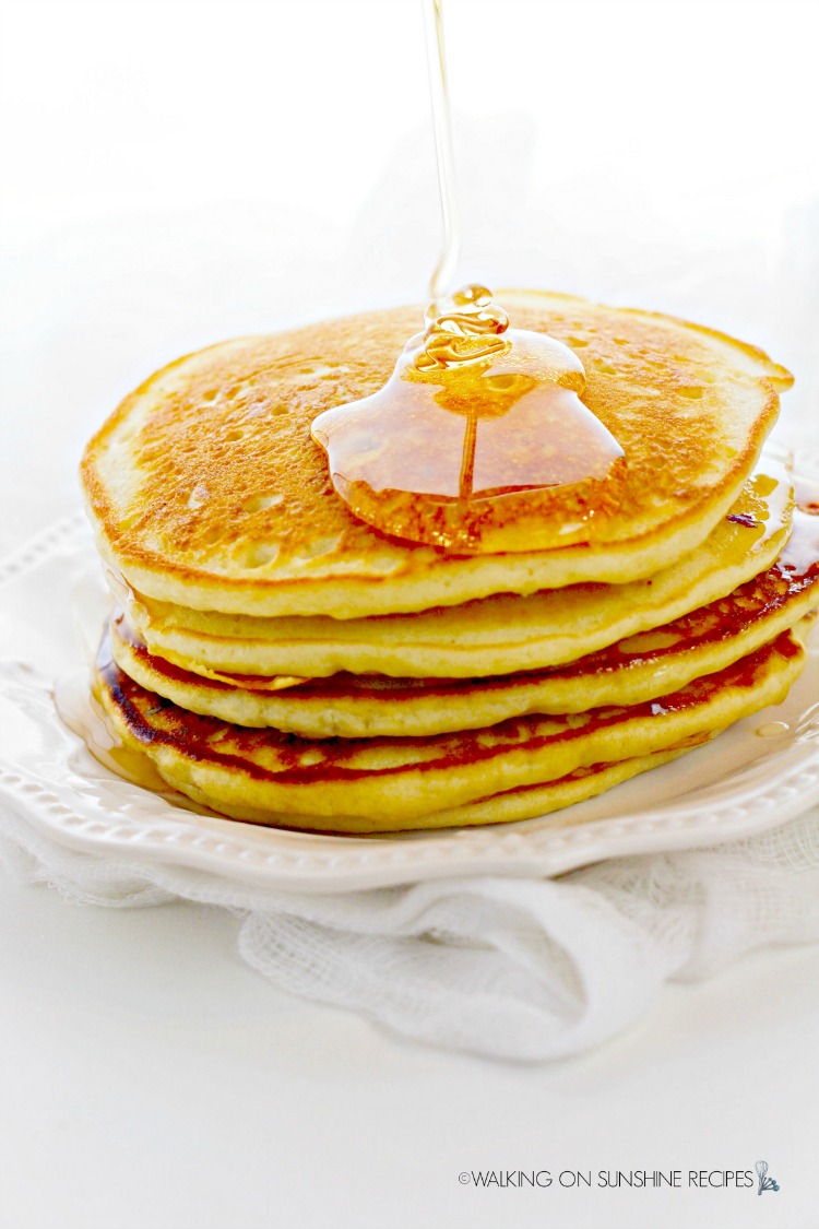 Fresh from the griddle buttermilk pancakes with syrup drizzled on top. 