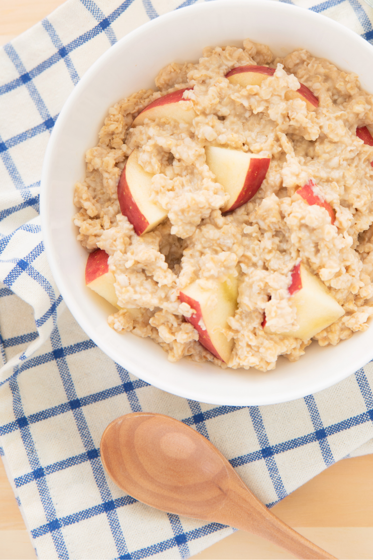 Bowl of oatmeal with sliced apples.