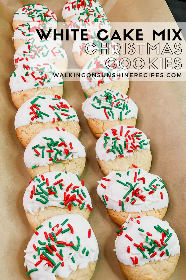 Cookies with white chocolate icing and sprinkles on top of brown parchment paper. 