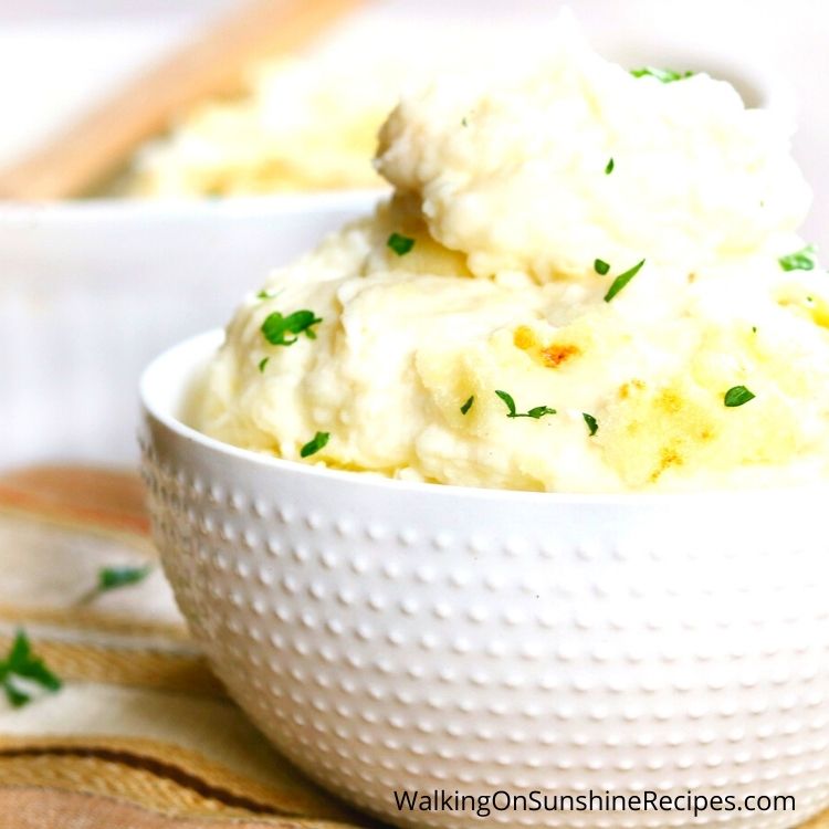 mashed potatoes with parsley flakes in white bowl.