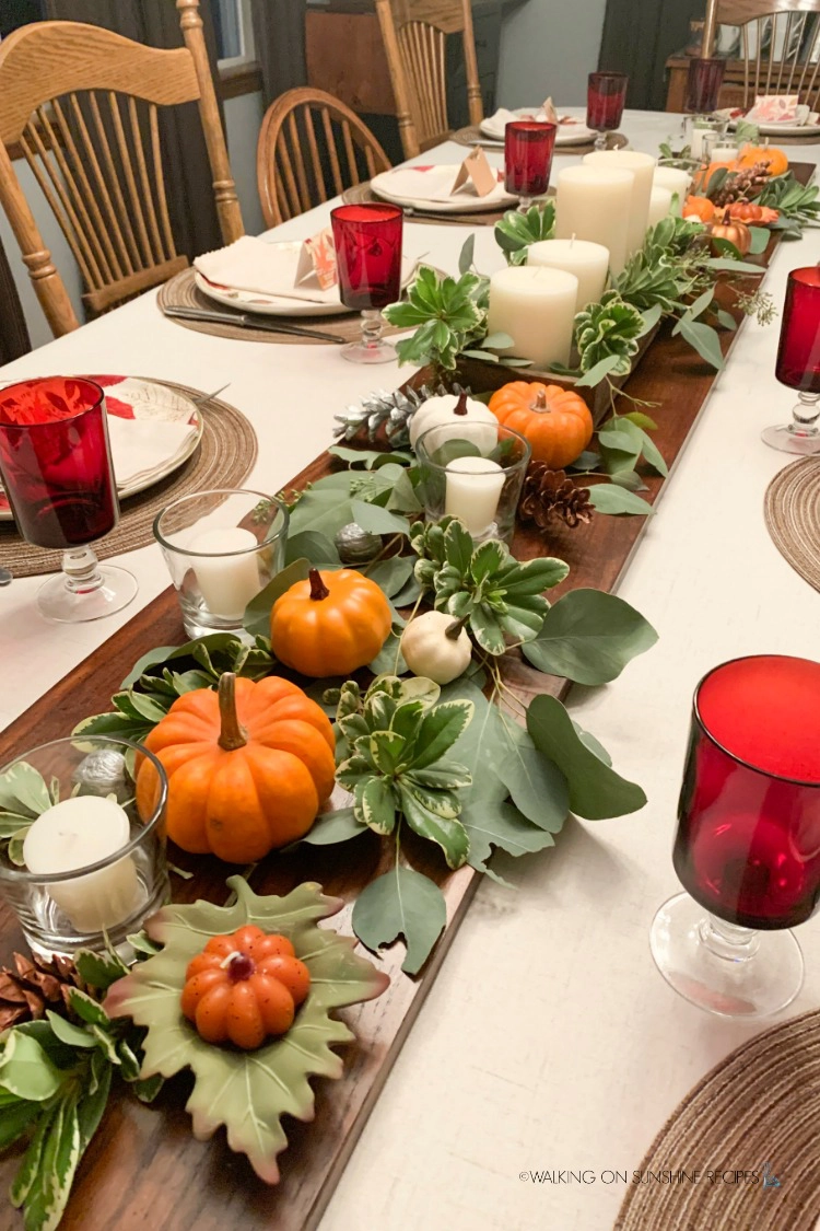 Thanksgiving table set with pumpkins, candles and greenery. 