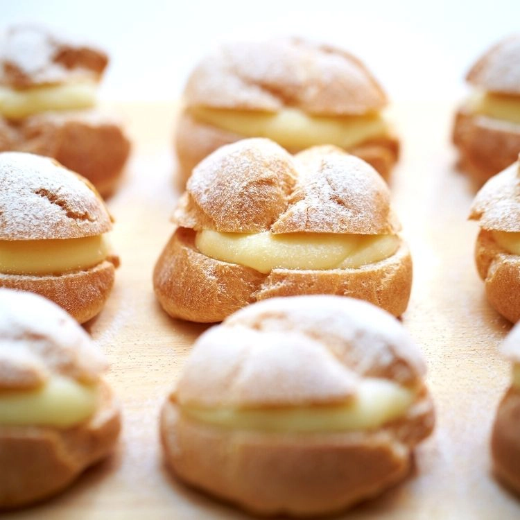homemade cream puffs filled with pudding on platter. 
