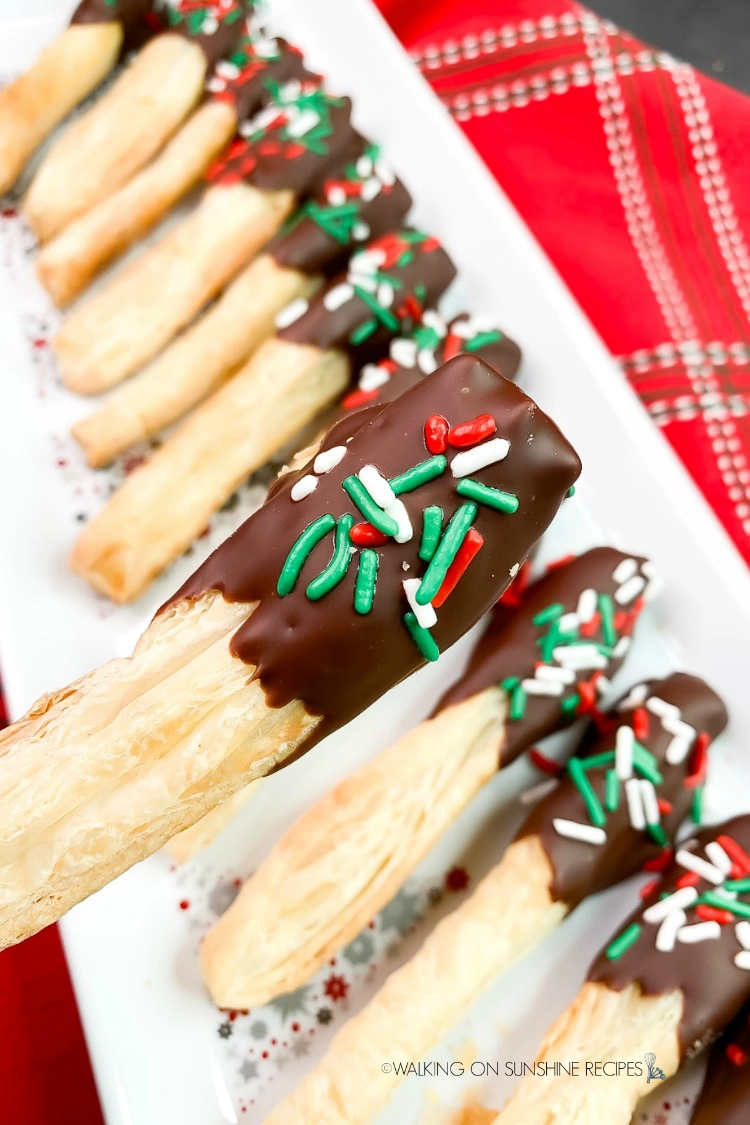 Puff Pastry Christmas Cookies dipped in melted chocolate and sprinkles on white platter