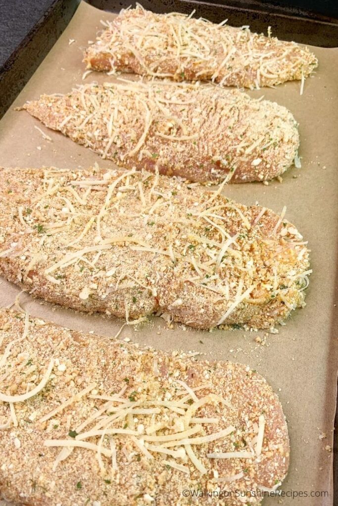 Chicken cutlets on parchment lined sheet pan before baking. 