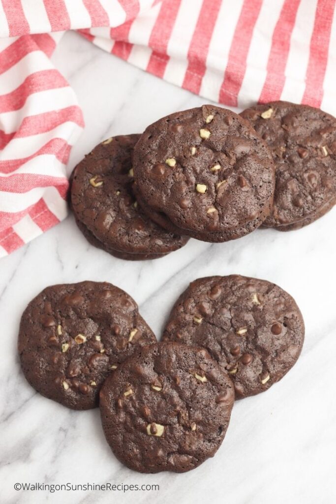Brownie mint chip cookies on white board with red and white napkin.