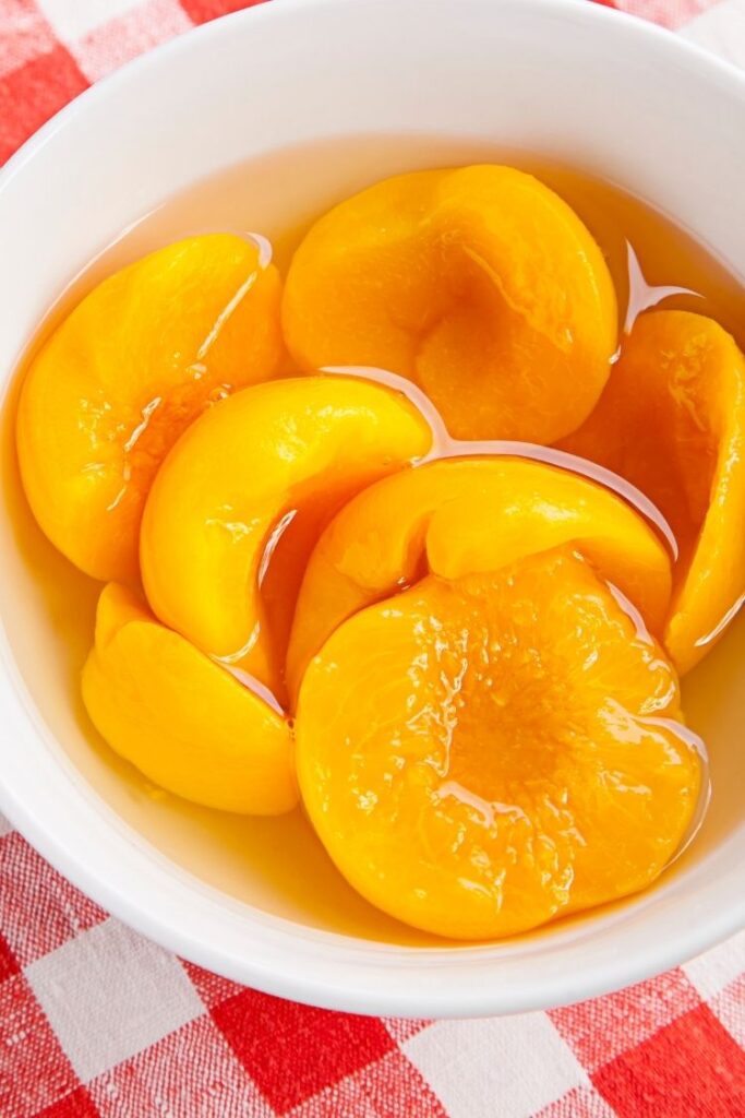 peaches in white bowl with juice.