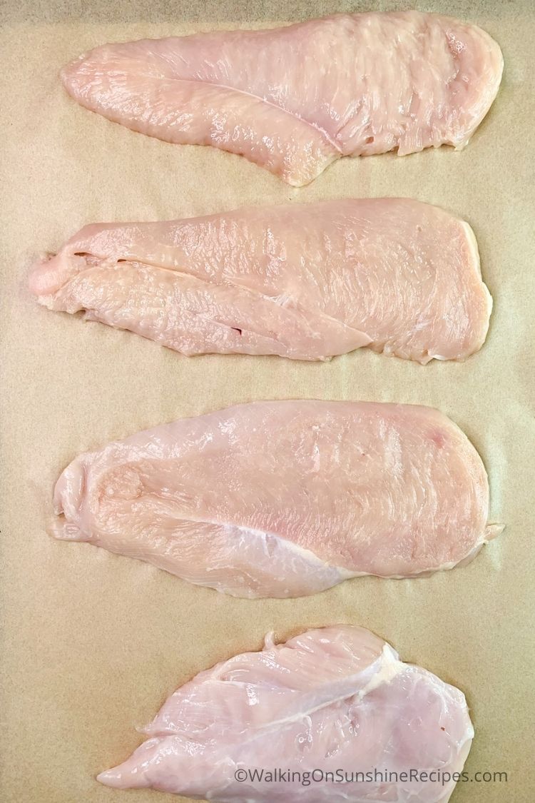Thin chicken cutlets on parchment paper. 