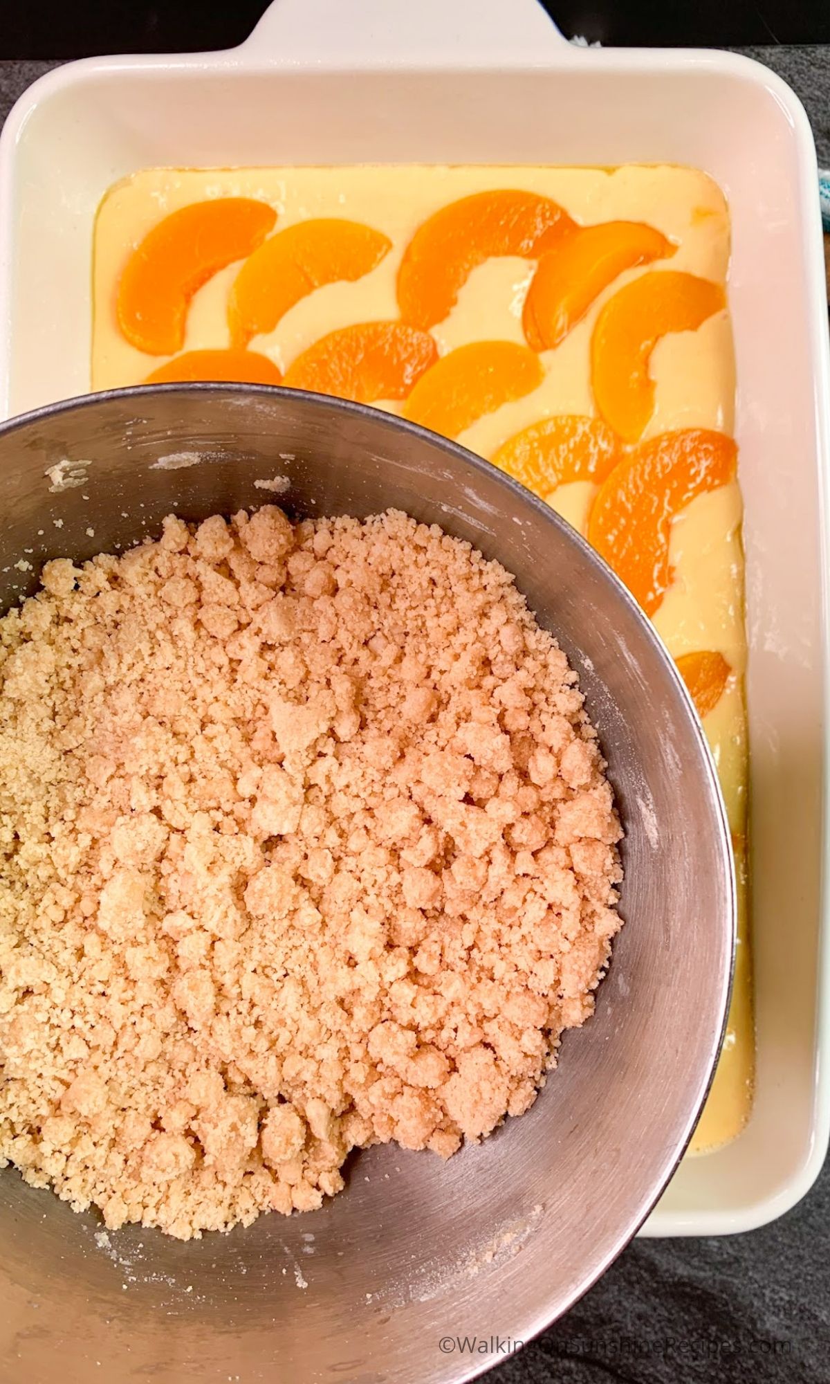 Add crumb mixture to the top of sliced canned peaches and cake batter.