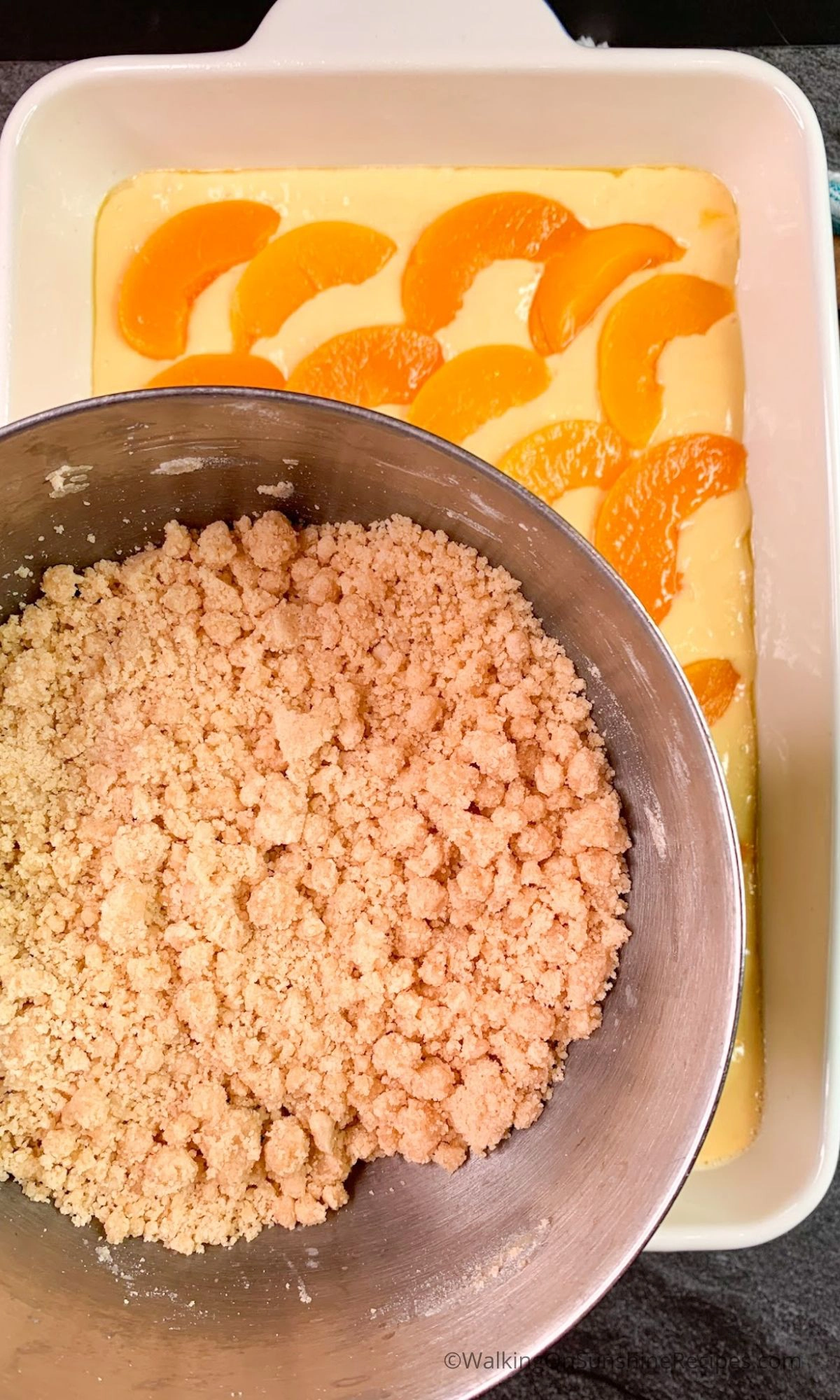 Add crumb mixture to the top of sliced canned peaches and cake batter. 