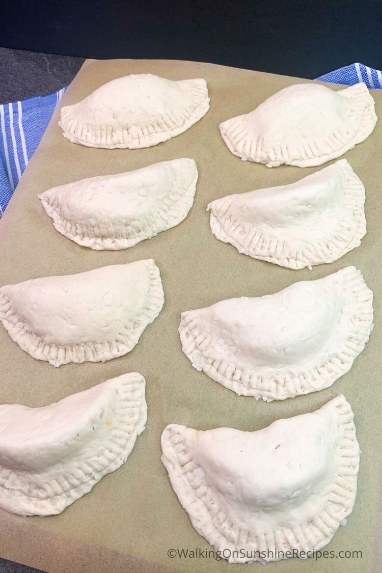 Hand pies made with canned peaches and canned biscuits on parchment line baking tray. 