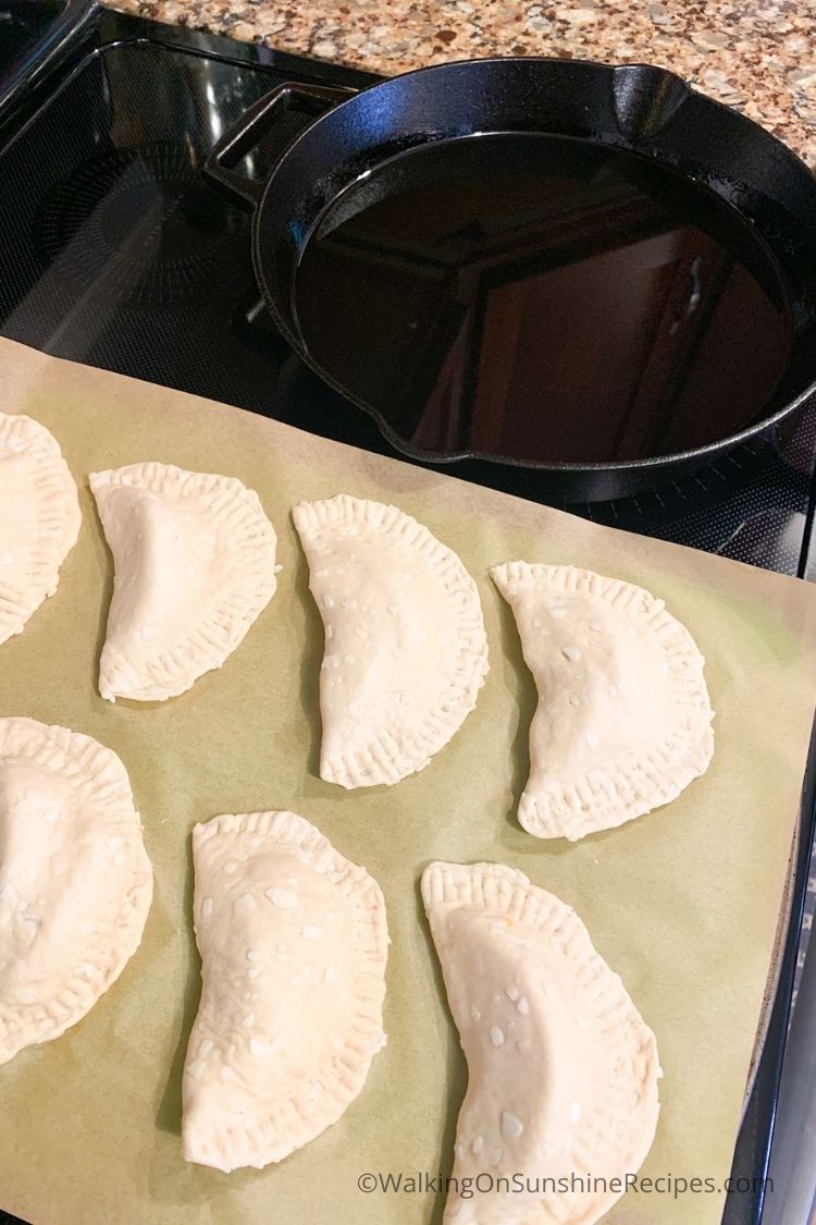 Biscuit hand pies on baking tray next to cast iron skillet. 