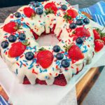 Add festive colored sprinkles to the top of the red velvet bundt cake from a cake mix.