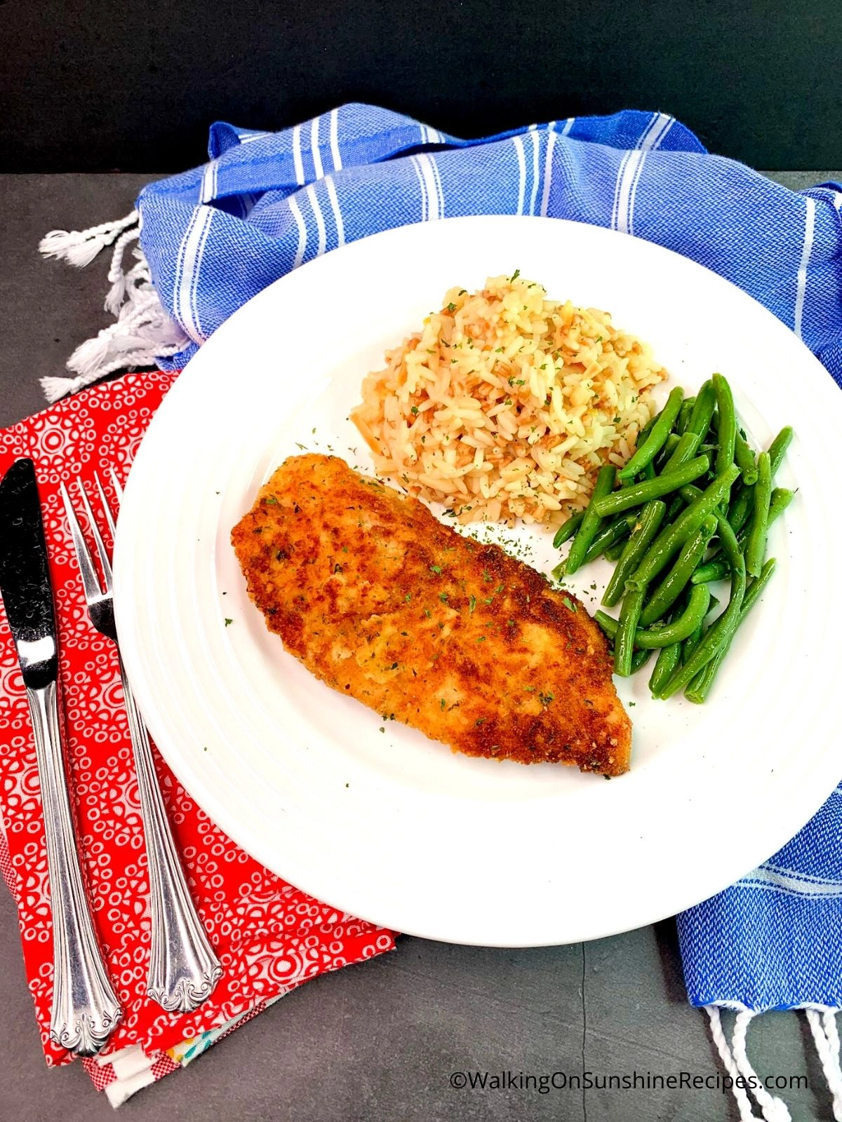 Breaded Chicken Cutlets on white plate with rice pilaf and steamed green beans.