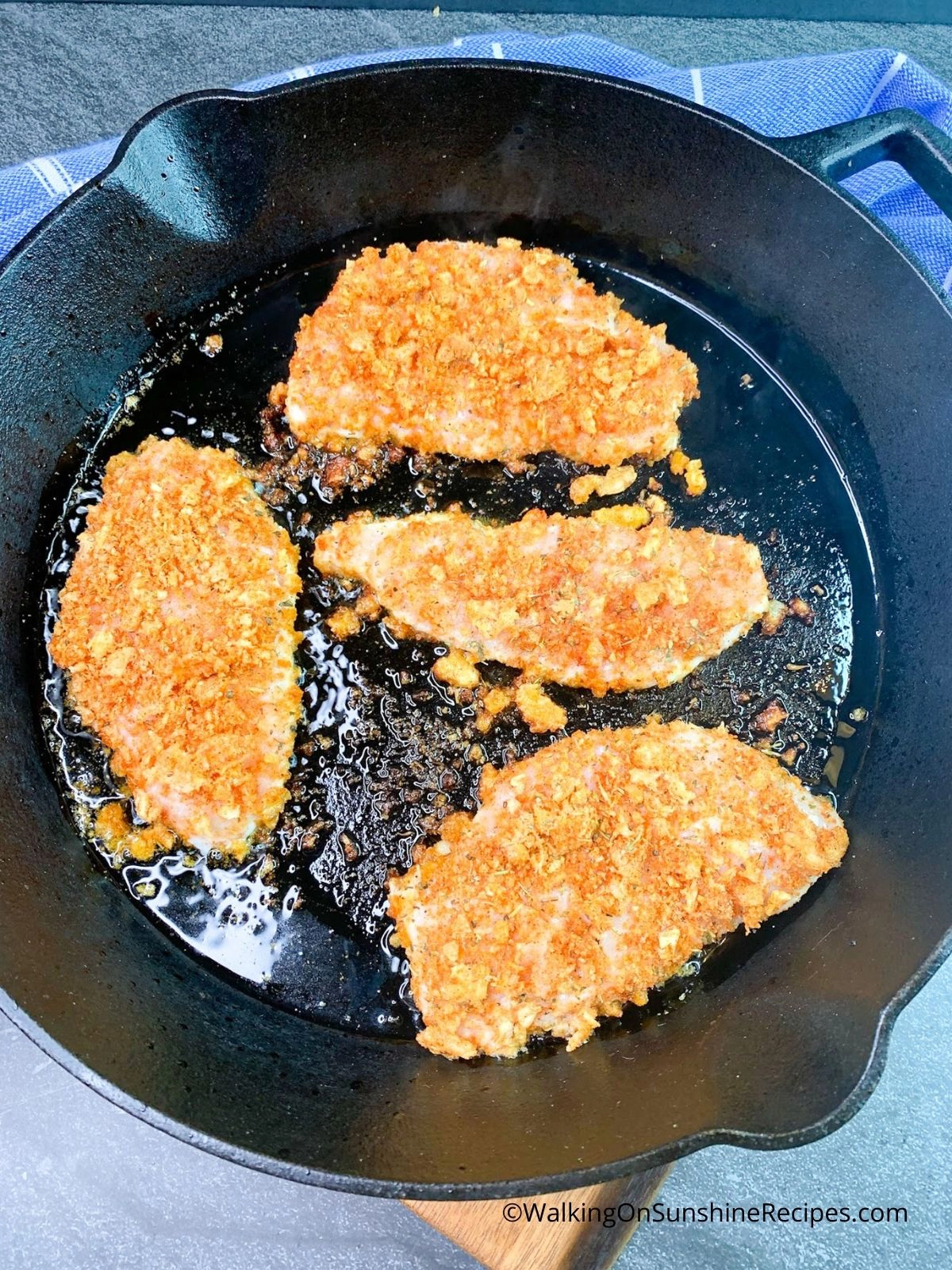 chicken cooking in cast iron skillet.