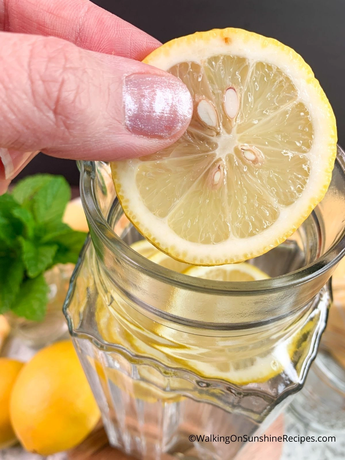 Add lemon slices to pitcher of water.