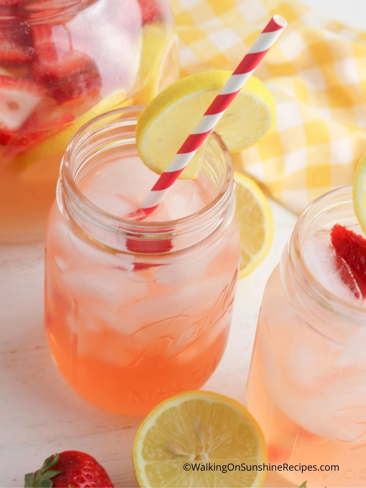 Infused strawberry lemonade in mason jars with red and white striped straws