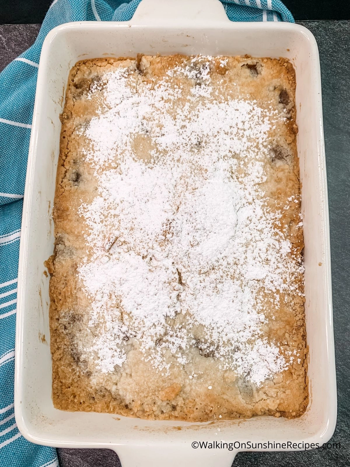 apple dump cake baked with powdered sugar on top. 