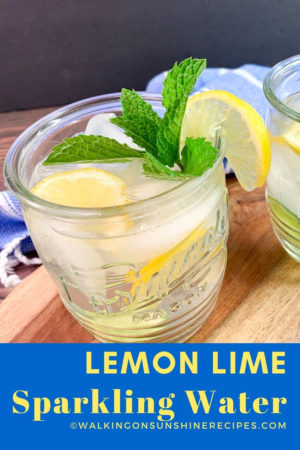 glass of lemon lime water with ice cubes and sprig of mint leaves. 