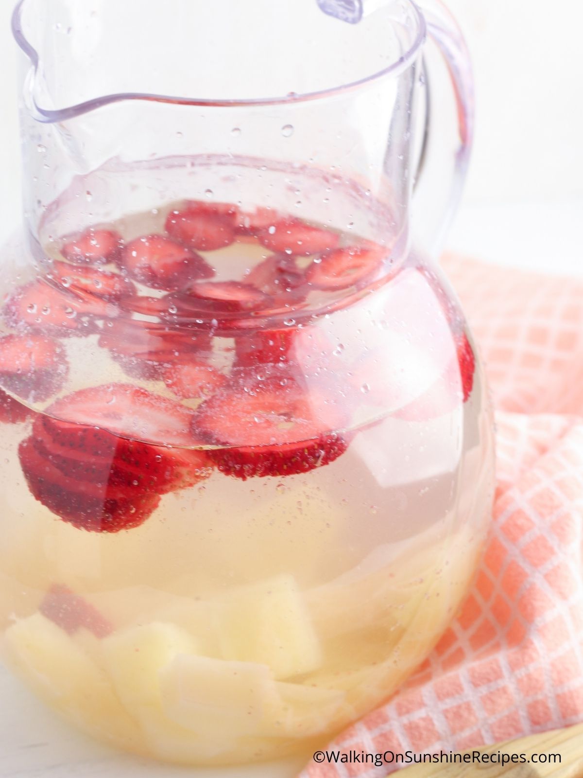 Strawberries and pineapples in pitcher.