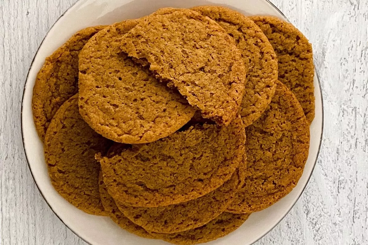 Plate filled with gingersnap cookies. The cookie on top is cut in half.