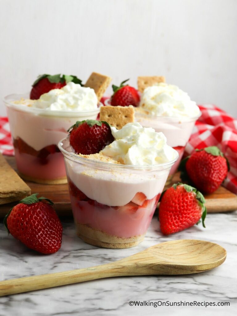 Pudding in cup with whipped cream and strawberries on top.
