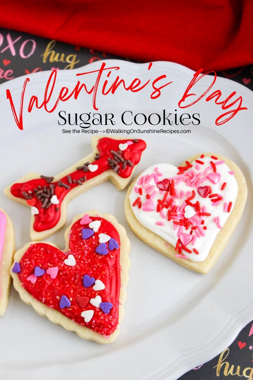 Sugar cookies in the shape of hearts and a cupid's arrow on white plate. 