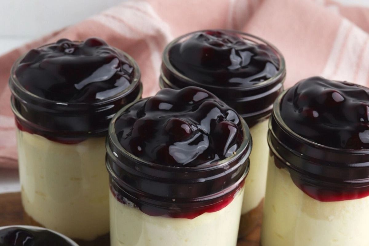 Individual cheesecake desserts served in glass jars.