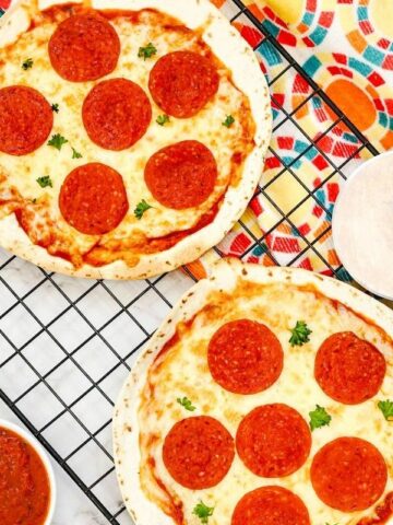 Pepperoni pizzas on a wire rack.