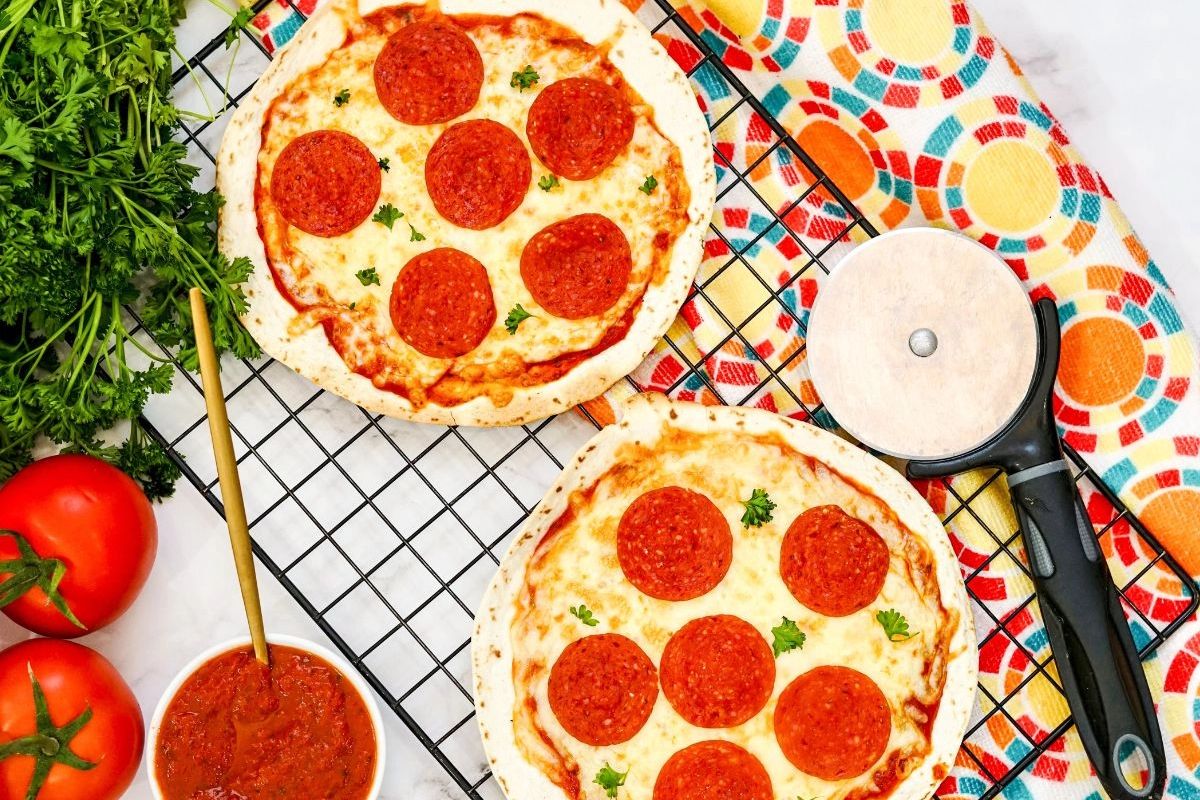 Pepperoni pizzas on a wire rack.