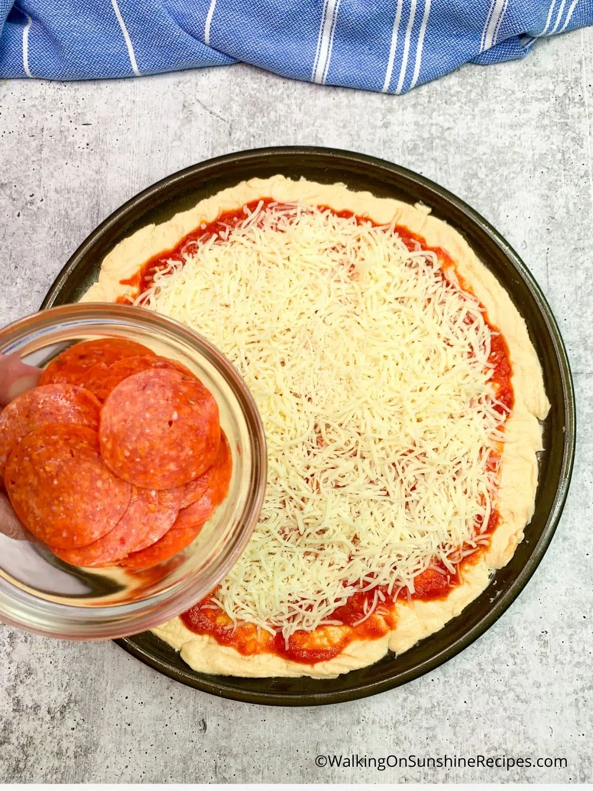 adding sliced pepperoni to pizza using pillsbury crescent rolls.