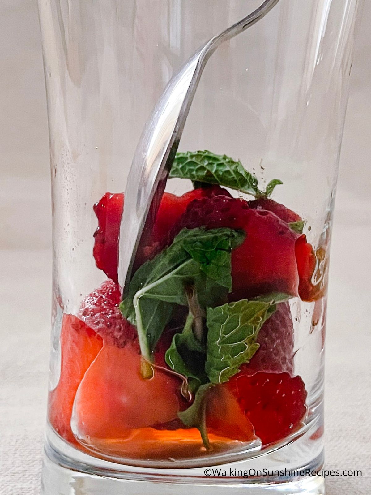 Crush mint leaves with the strawberries.